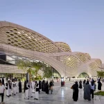 Visitors outside KAFD Metro Station beneath its flowing lattice façade at dusk