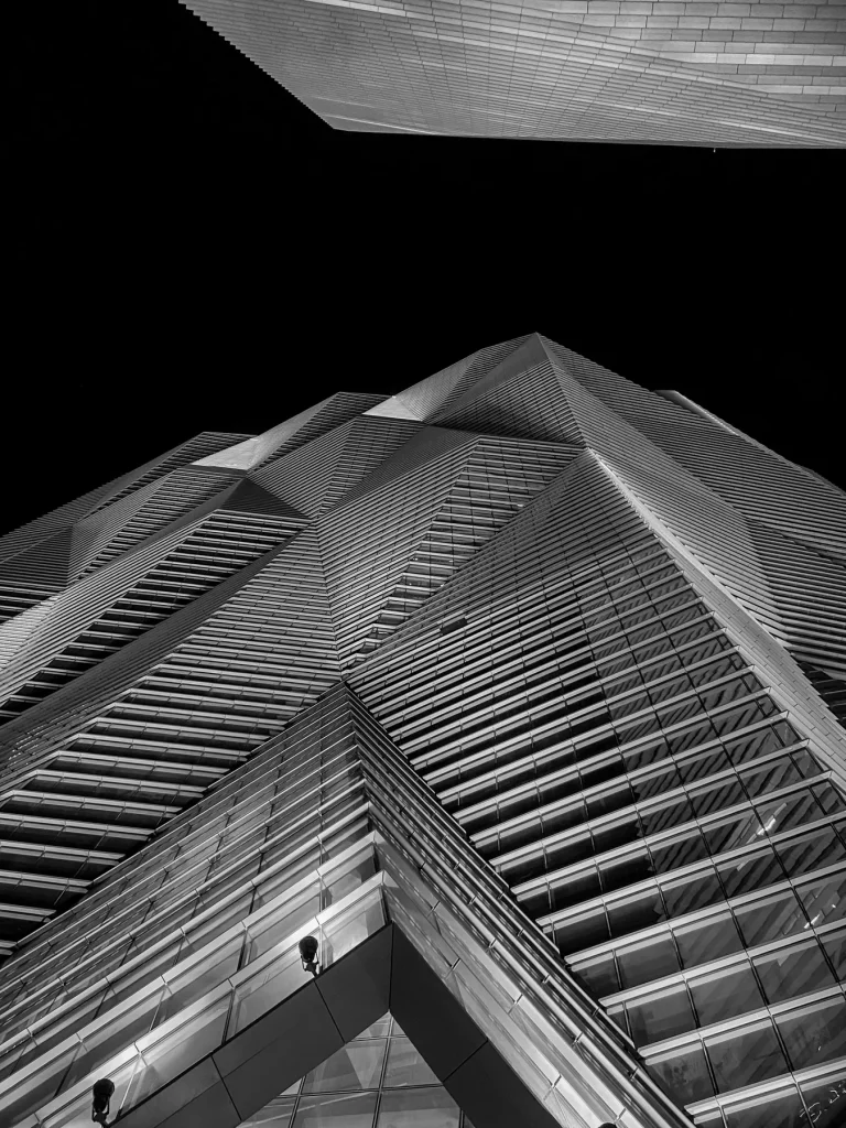 Black-and-white view looking up at angular tower façades at KAFD