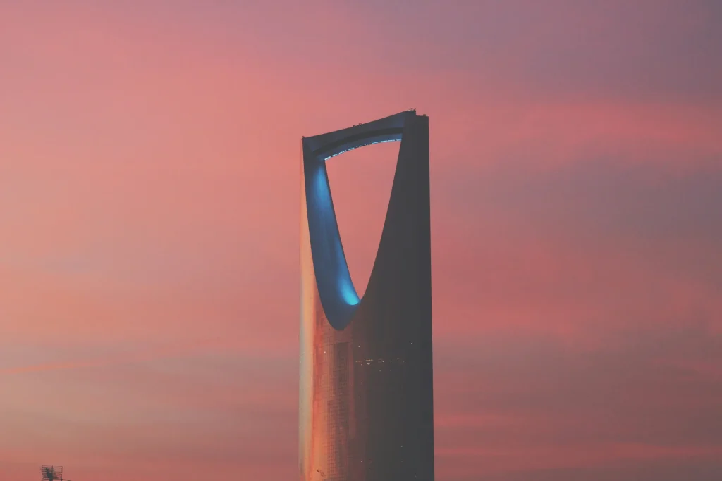 The upper section of Kingdom Centre against a pink evening sky