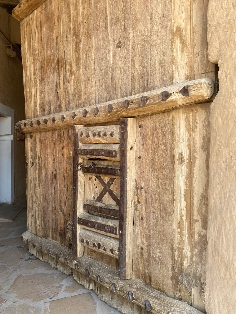 Large timber door at Al Masmak with iron studs and a smaller inset doorway