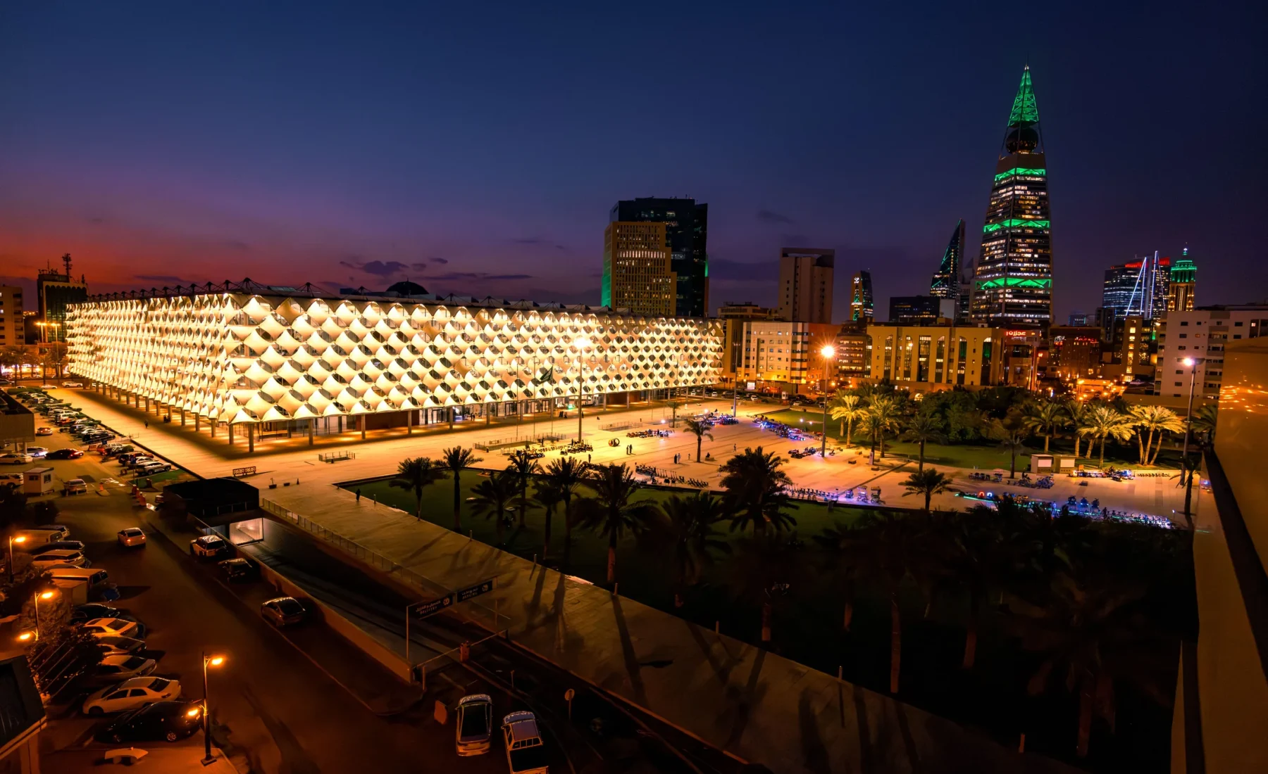 Illuminated patterned building facade and Riyadh towers at dusk