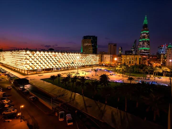 Illuminated patterned building facade and Riyadh towers at dusk