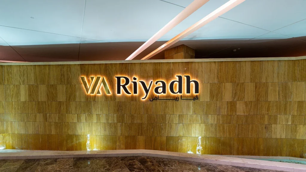 Illuminated VIA Riyadh sign in English and Arabic above a water feature